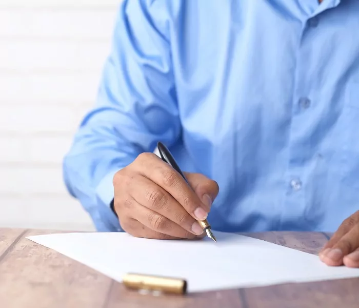 Man in a blue dress shirt signing a document